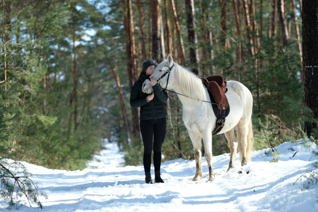 Woman and horse walking in snowy wood